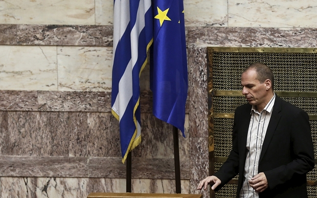 Greek Finance Minister Yanis Varoufakis walks next to a European Union and a Greek national flag during a parliamentary session in Athens April 2, 2015. Greece sent an updated list of reforms to lenders on Wednesday to try to unlock financial aid and avoid a default but euro zone officials said more work was needed before new funds could be released. REUTERS/Alkis Konstantinidis