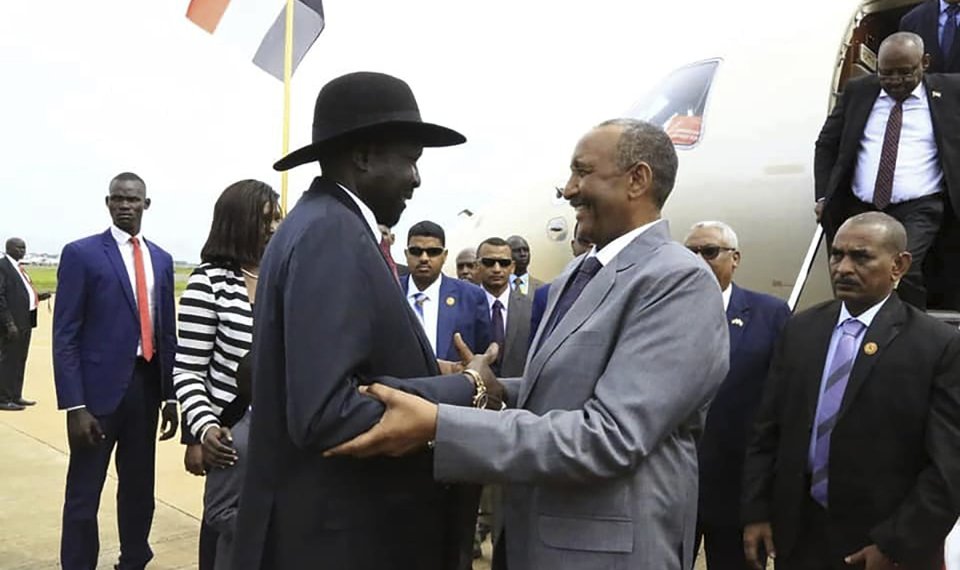 In this photo provided by the official SUNA news agency, Gen. Abdel-Fattah Burhan, center right, head of Sudan’s sovereign council, is greeted by South Sudan’s President Salva Kiir, center left, in Juba, South Sudan, Monday, Oct. 14, 2019. Sudan's new transitional government is starting talks Monday with rebel leaders in South Sudan's capital, Juba to kick off peace talks aimed at ending the country's yearslong civil wars. Achieving peace is crucial to the transitional government in Sudan. It has counted on ending the wars with rebels in order to revive the country's battered economy through slashing the military spending, which takes up much of the national budget. (SUNA via AP)