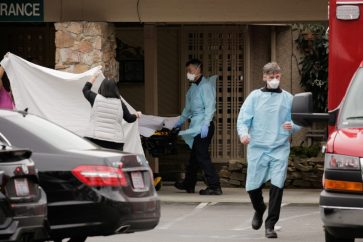 Medics transfer a patient on a stretcher to an ambulance at the Life Care Center of Kirkland, the long-term care facility linked to the two of three confirmed coronavirus cases in the state, in Kirkland