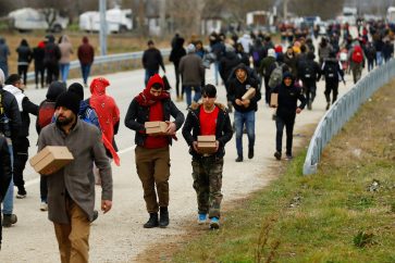 Migrants walk with boxes of food delivered by members of United Nations High Commissioner for Refugees at the Turkey's Pazarkule border crossing with Greece's Kastanies, in Edirne, Turkey, February 29, 2020. REUTERS/Huseyin Aldemir - RC2FAF9OGDW7