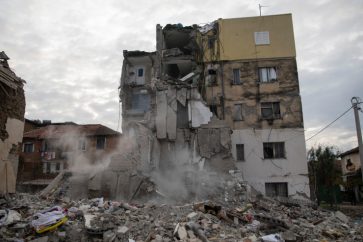 Dust rises from falling parts of a destroyed building during an aftershock in Thumane, western Albania, Wednesday, Nov. 27, 2019.  A deadly earthquake struck in the coastal cities of Albania, early Tuesday, killing at least 27 people and injuring more than 650. (AP Photo/Petros Giannakouris)