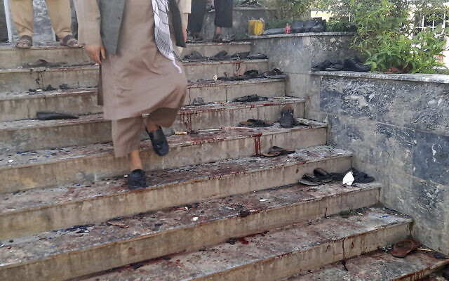 A man walks down blood-stained steps of a mosque following a bombing in Kunduz province, northern Afghanistan, Friday, Oct. 8, 2021. A powerful explosion in a mosque frequented by a Muslim religious minority in northern Afghanistan on Friday has left several casualties, witnesses and the Taliban's spokesman said. (AP Photo/Abdullah Sahil)
