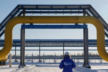 FILE PHOTO: An employee in branded jacket walks past a part of Gazprom's Power Of Siberia gas pipeline at the Atamanskaya compressor station outside the far eastern town of Svobodny, in Amur region, Russia November 29, 2019. REUTERS/Maxim Shemetov./File Photo