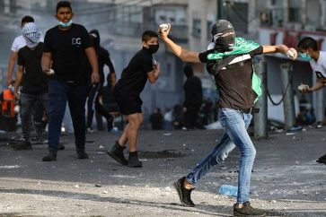 Palestinian youths hurl rocks toward Israeli occupation forces during raid in the Shuafat refugee camp in east Al-Quds on October 12, 2022.