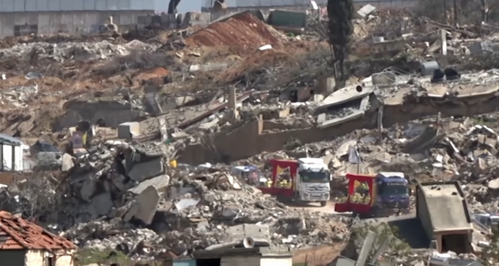 Trucks carrying bodies of 50 martyrs pass through Kfarkila streets filled with debris left by the Israeli war